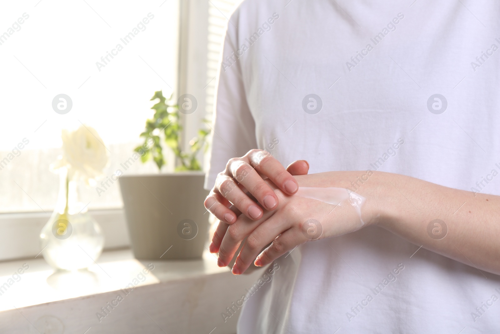 Photo of Woman applying hand cream at home, closeup