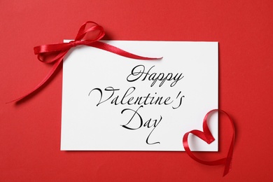 Image of Greeting card with text Happy Valentine's Day and ribbons on red background, flat lay