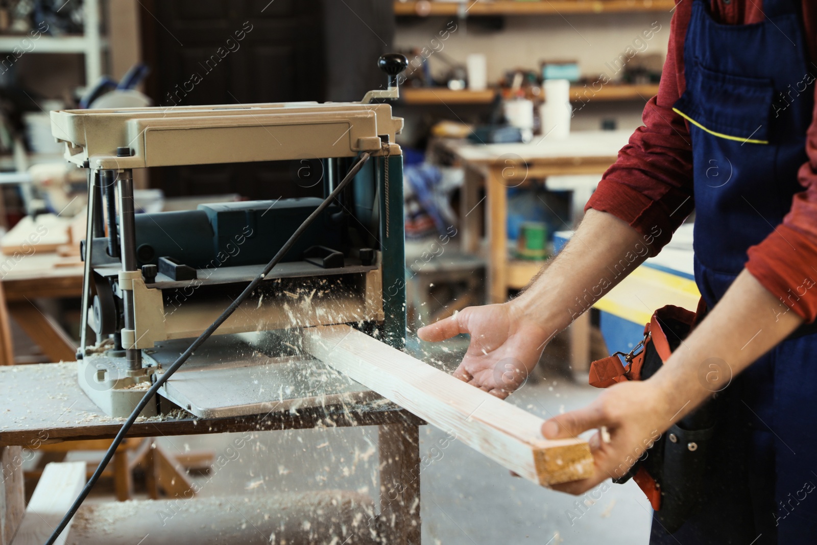 Photo of Working man using thickness planer at carpentry shop, closeup