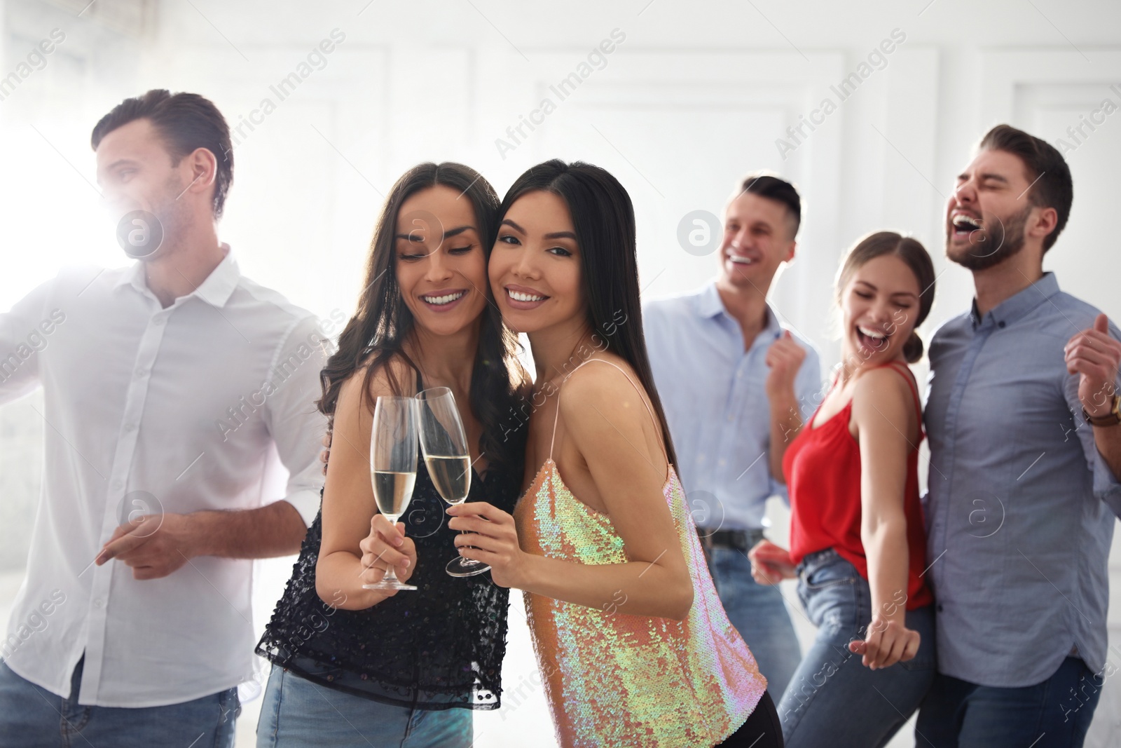 Photo of Couple of happy friends with champagne dancing at party