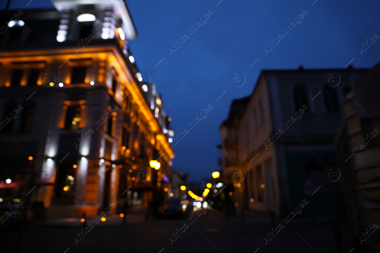 Photo of Blurred view of beautiful cityscape with glowing streetlights and illuminated building in evening