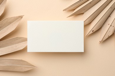 Blank business card and decorative plants on beige background, flat lay. Mockup for design