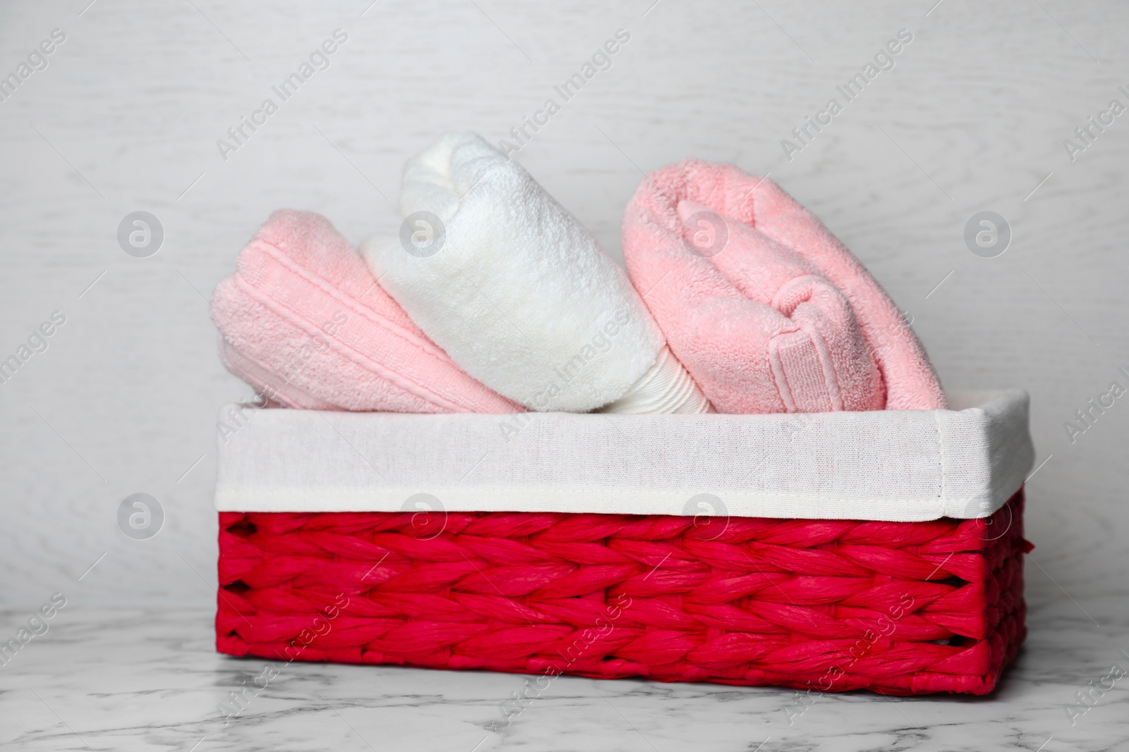 Photo of Basket with soft bath towels on table