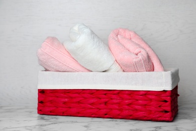 Photo of Basket with soft bath towels on table