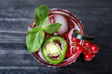 Spicy red currant cocktail with jalapeno and mint on black wooden table, top view