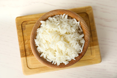 Photo of Bowl with cooked rice on white wooden table, flat lay