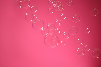 Photo of Beautiful translucent soap bubbles on pink background