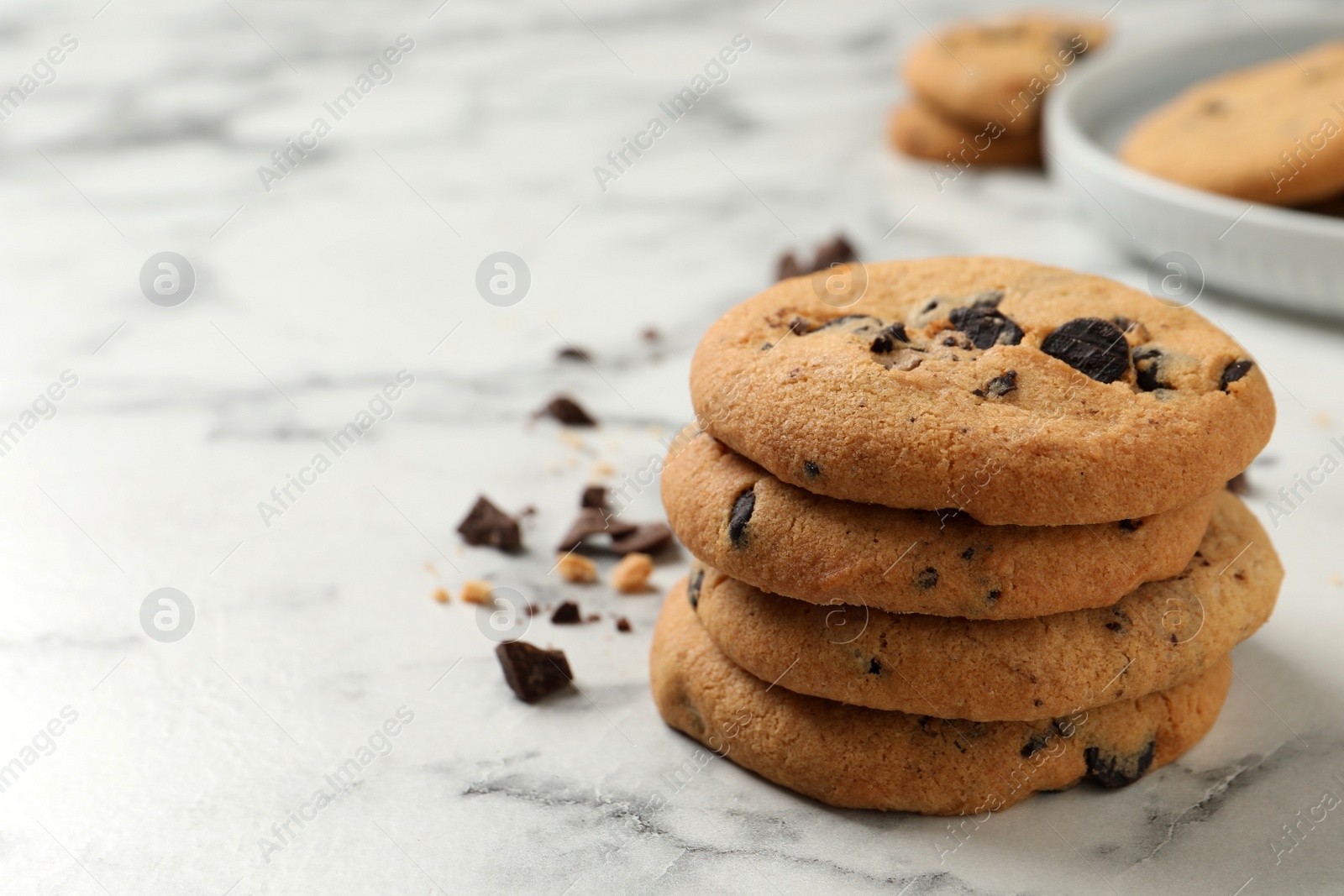 Photo of Delicious chocolate chip cookies on white marble table. Space for text