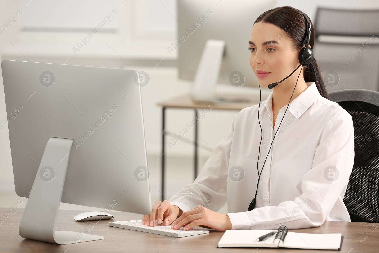 Photo of Hotline operator with headset working on computer in office