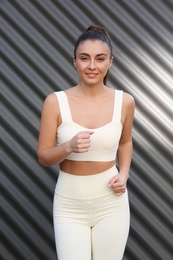 Young woman in sportswear near corrugated metal wall