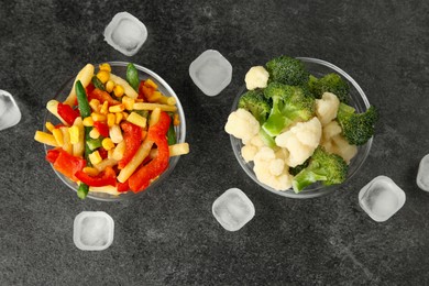 Photo of Bowls of different frozen vegetables and ice cubes on grey table, flat lay