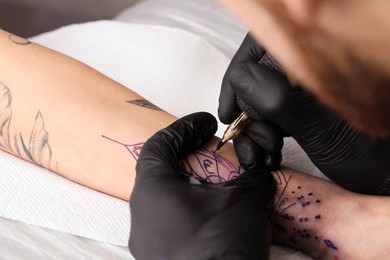 Professional artist making tattoo on hand at table, closeup