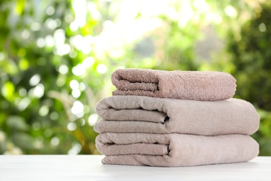 Photo of Stack of clean soft towels on table against blurred background. Space for text