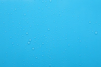 Water drops on light blue background, top view