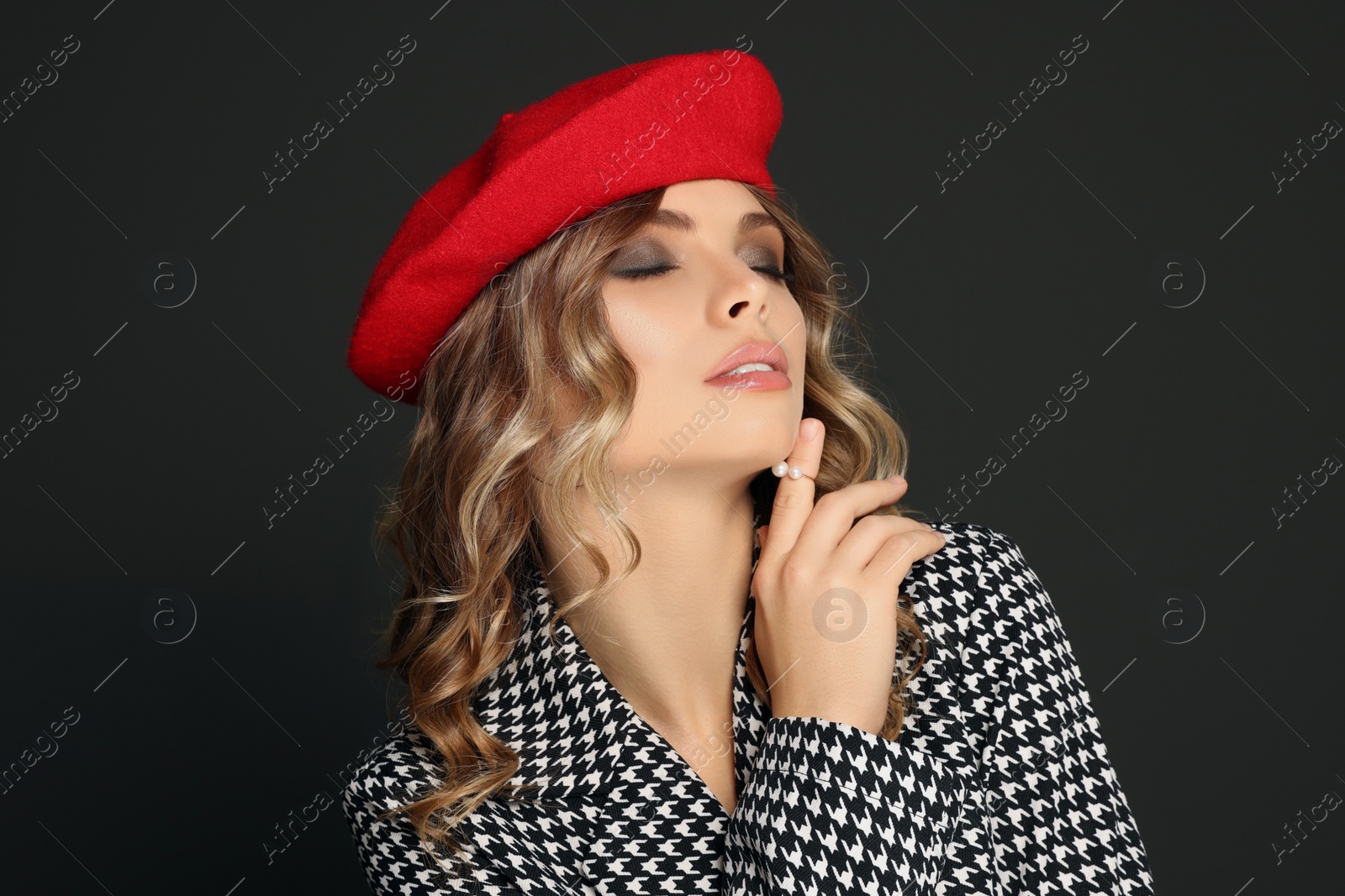 Photo of Young woman with beautiful makeup in red beret against black background