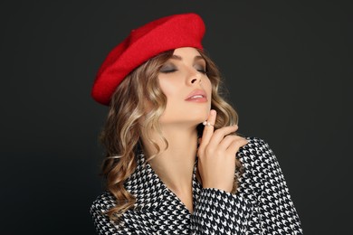 Young woman with beautiful makeup in red beret against black background