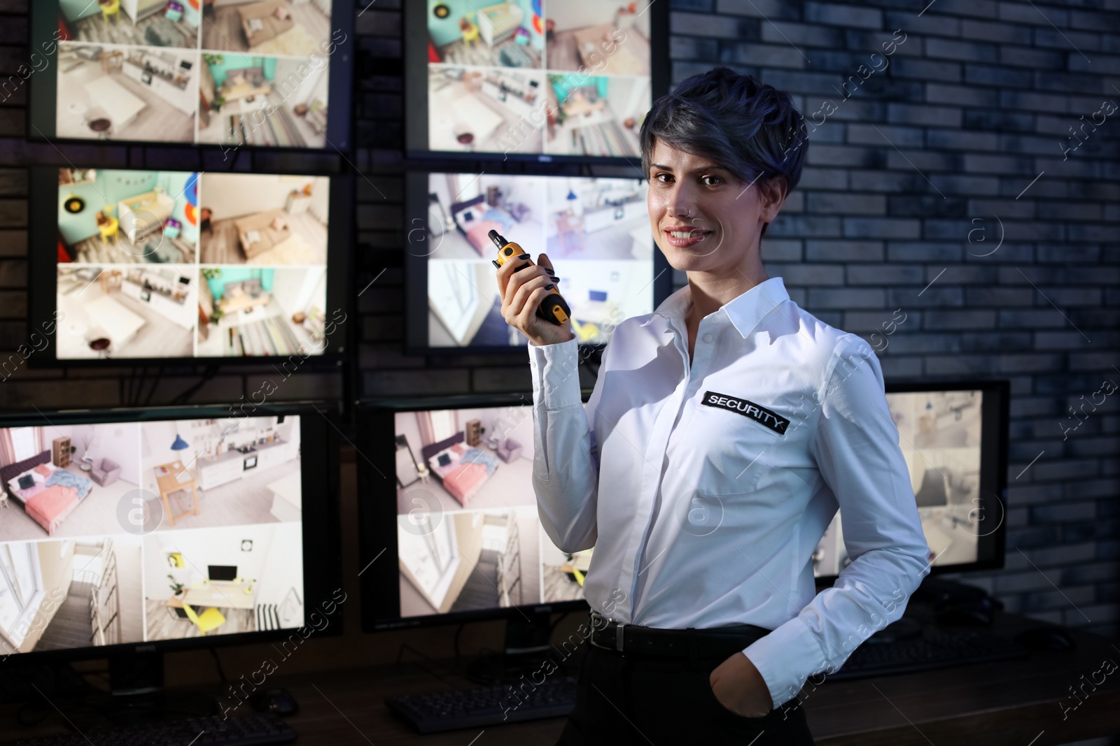 Photo of Female security guard with portable transmitter near cameras indoors