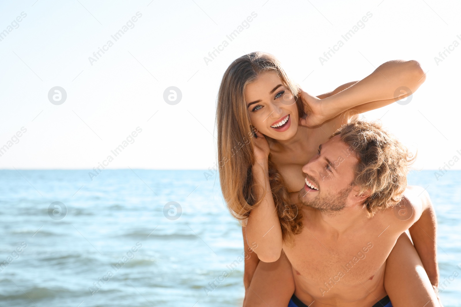 Photo of Happy young couple in beachwear having fun together on seashore. Space for text