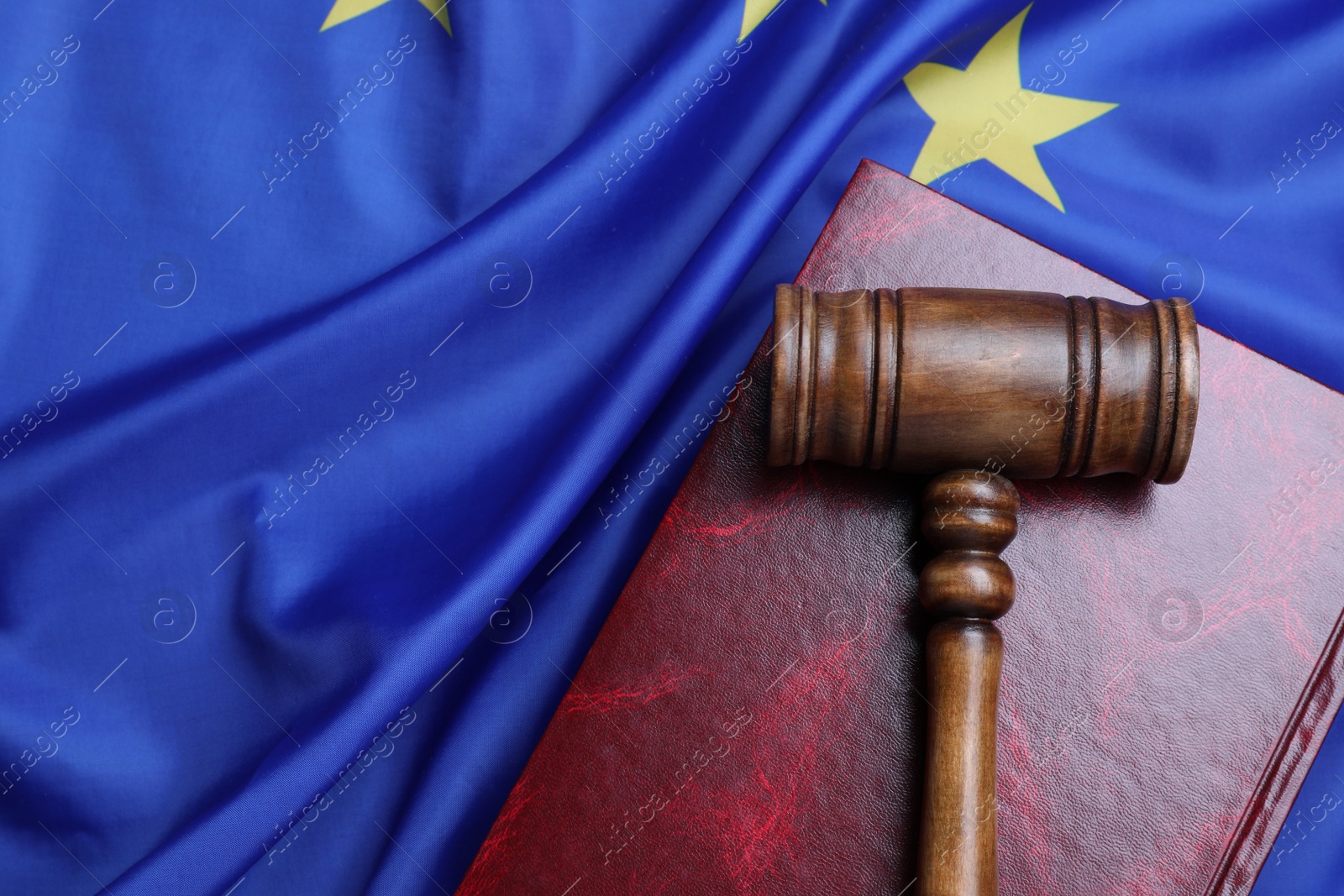 Photo of Wooden judge's gavel and book on flag of European Union, top view. Space for text