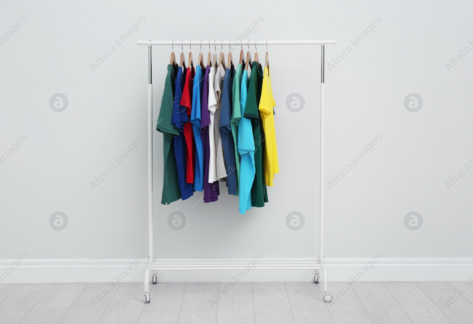 Photo of Rack with stylish colorful t-shirts in room