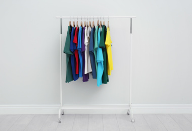 Photo of Rack with stylish colorful t-shirts in room