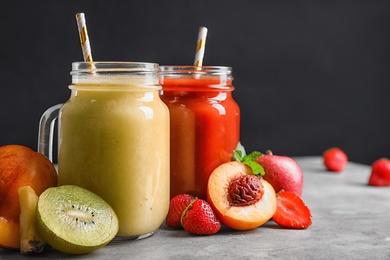 Delicious juices and fresh ingredients on grey table against black background