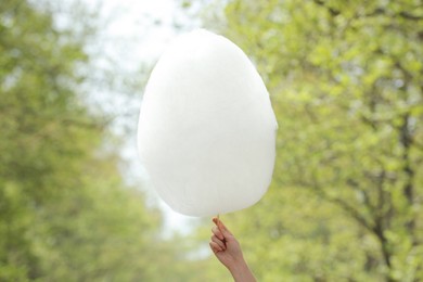 Photo of Woman holding sweet cotton candy outdoors, closeup