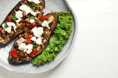 Plate of stuffed eggplants and space for text on light table, top view