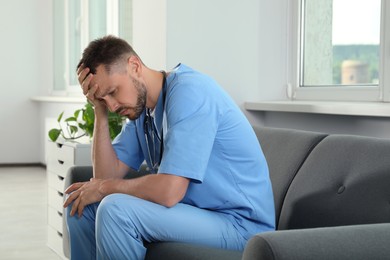 Exhausted doctor sitting on sofa in hospital