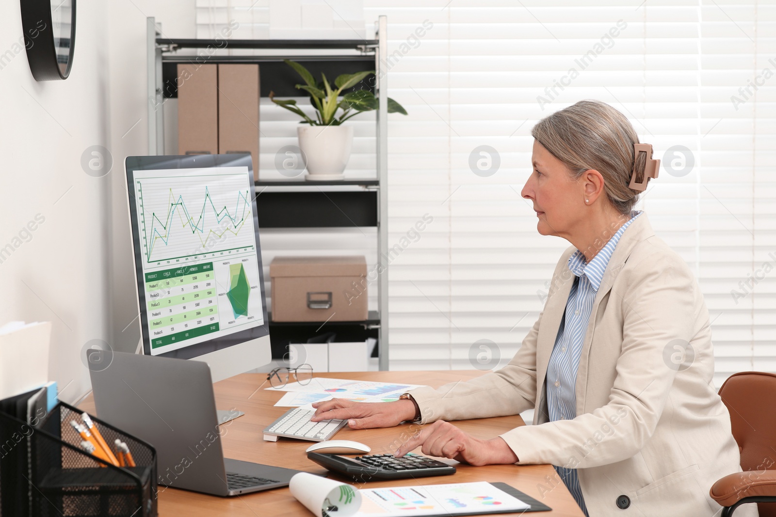 Photo of Senior accountant working at wooden desk in office