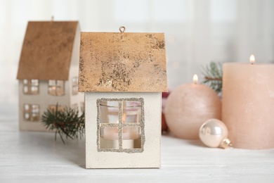 Photo of Composition with candles in house shaped holders on white wooden table. Christmas decoration