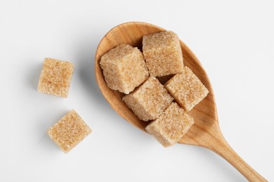 Photo of Brown sugar cubes in wooden spoon on white background, top view