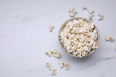 Bowl of tasty popcorn on white marble table, flat lay. Space for text