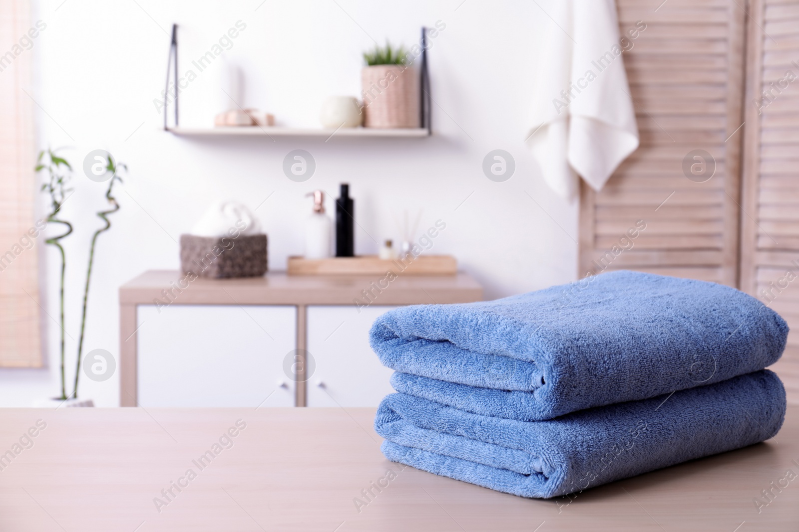 Photo of Stack of fresh towels on table in bathroom. Space for text