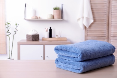 Photo of Stack of fresh towels on table in bathroom. Space for text