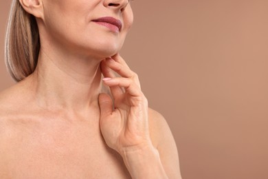 Photo of Woman touching her neck on beige background, closeup. Space for text