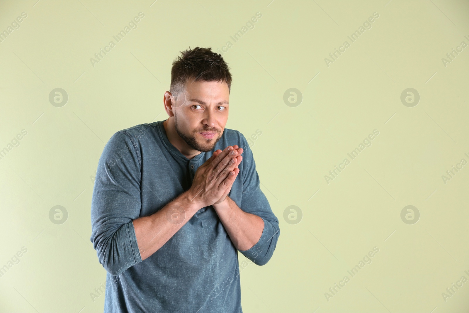 Photo of Greedy man rubbing hands on light background, space for text