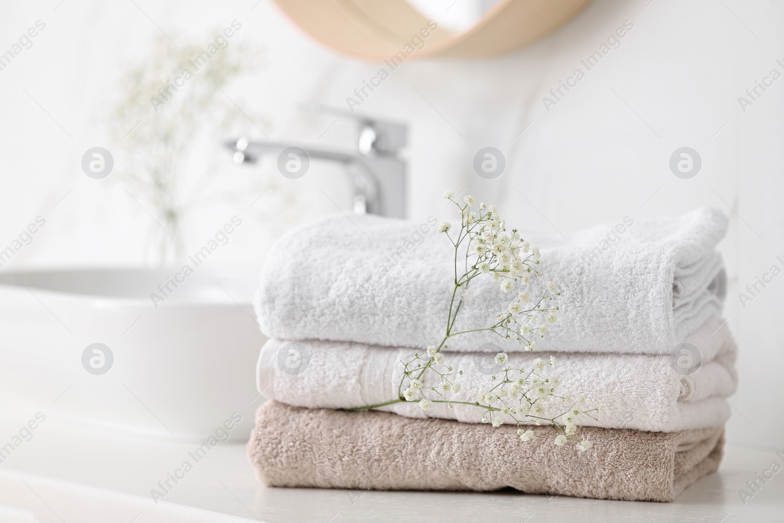 Photo of Clean towels and flowers on counter in bathroom