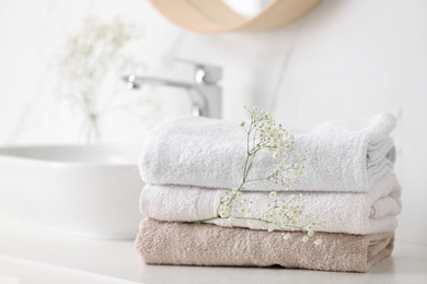 Photo of Clean towels and flowers on counter in bathroom
