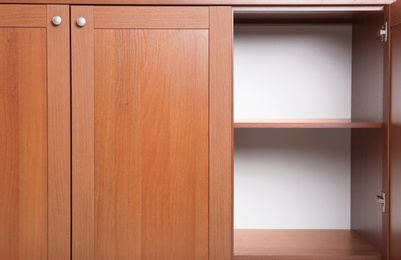 Photo of Open wooden wardrobe with empty shelves, closeup