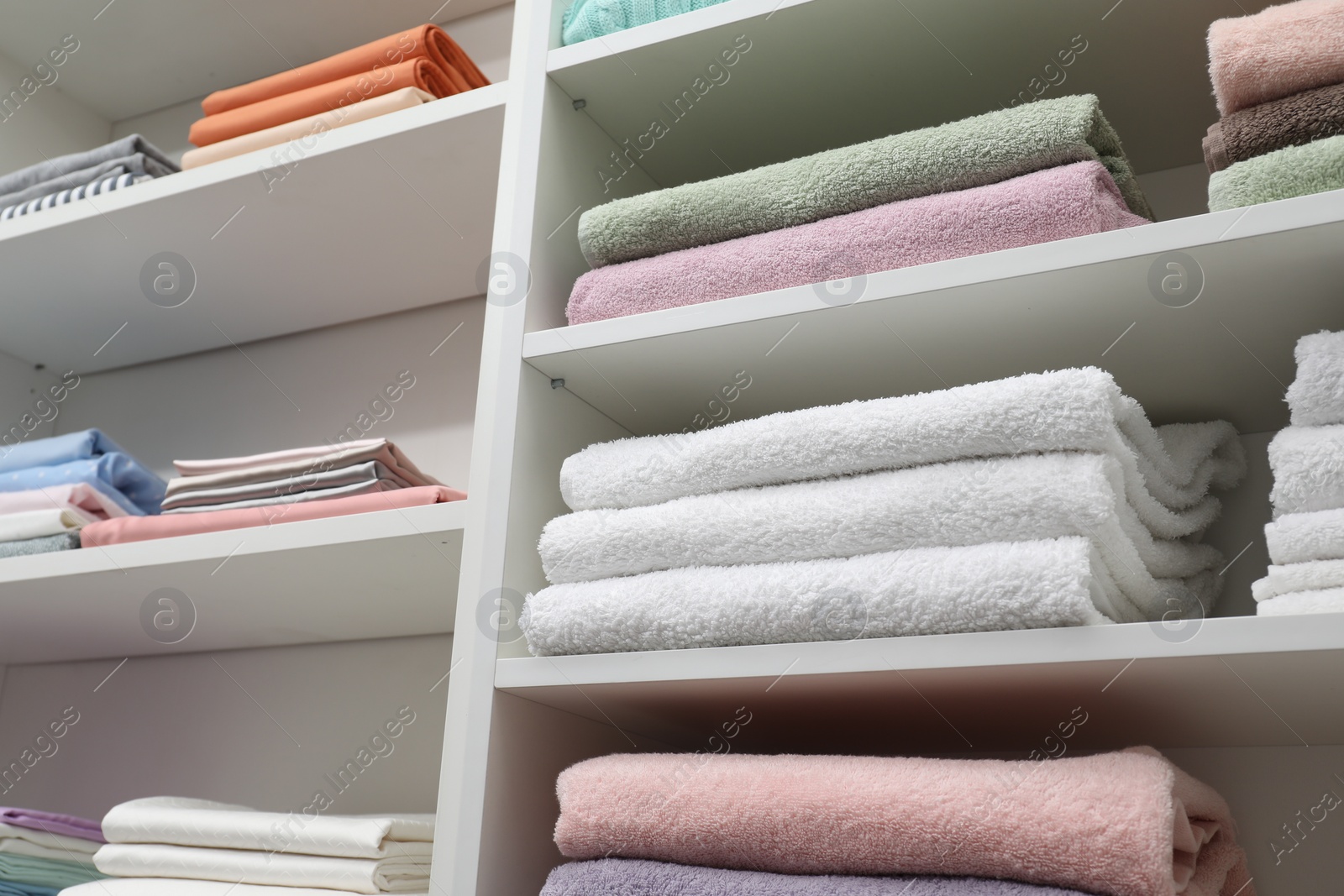 Photo of Bed linens and towels on shelves in shop, low angle view