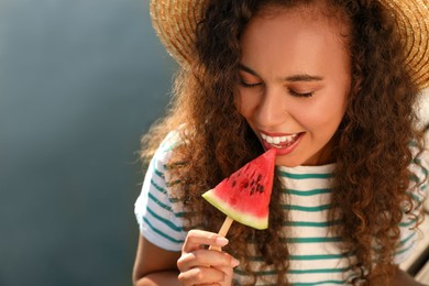 Photo of Beautiful young African American woman with piece of watermelon near river, closeup