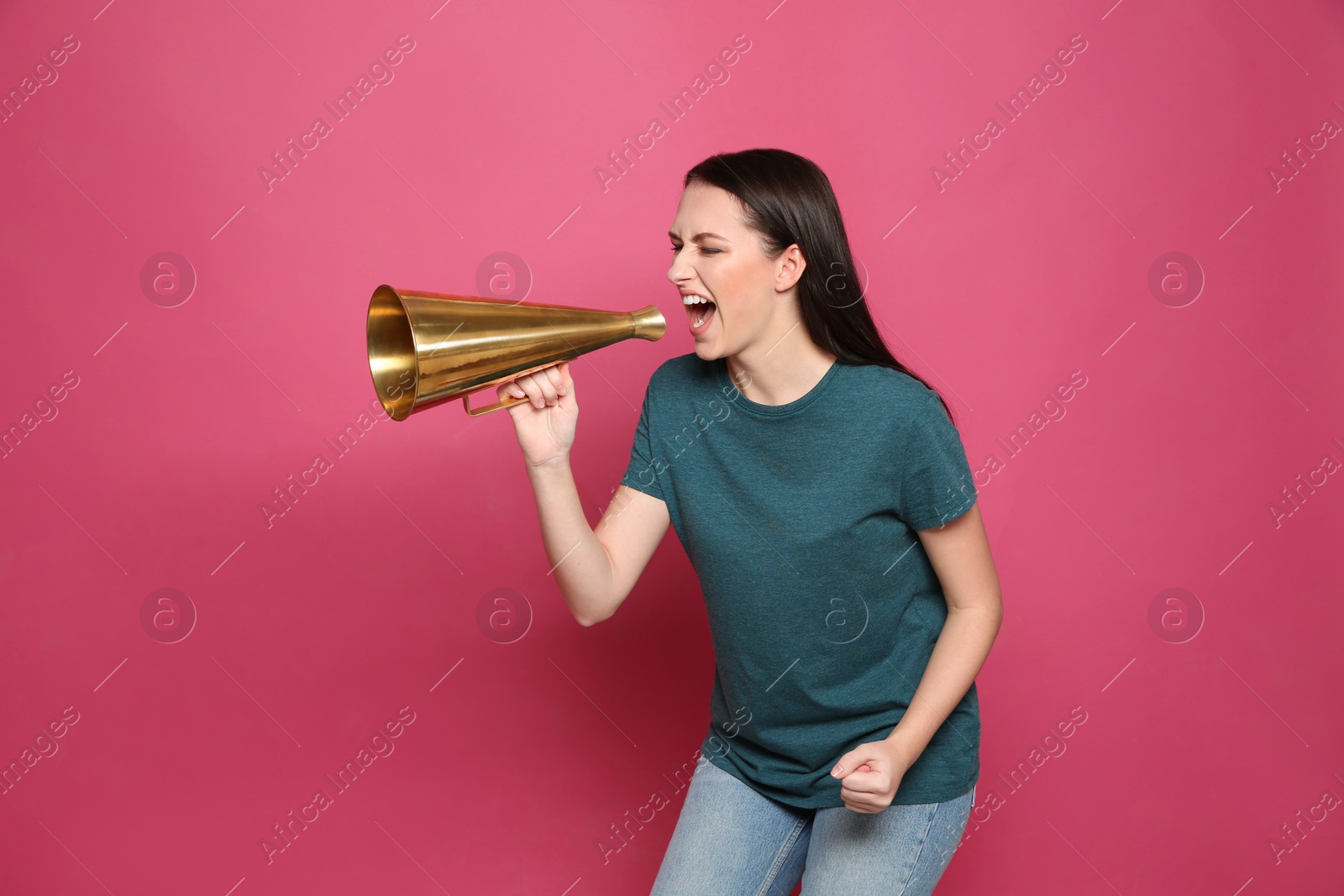 Photo of Emotional young woman with megaphone on color background