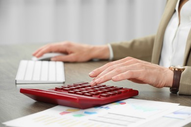 Photo of Professional accountant using calculator at wooden desk in office, closeup