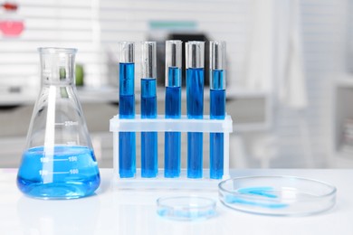 Photo of Laboratory analysis. Different glassware with blue liquid on white table indoors