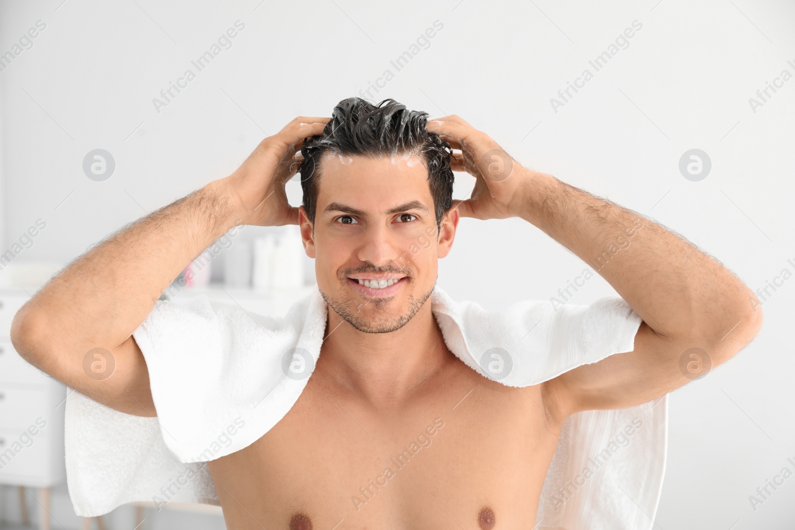 Photo of Man applying shampoo onto his hair against light background