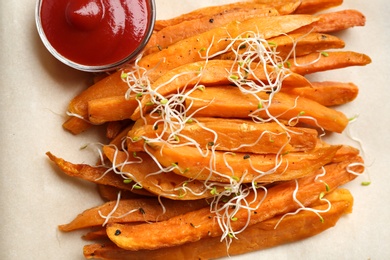 Tasty sweet potato fries on parchment, top view