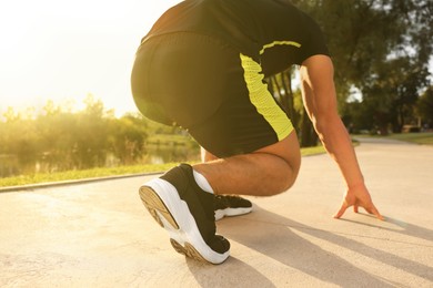 Photo of Runner on starting position in park on sunny day, closeup