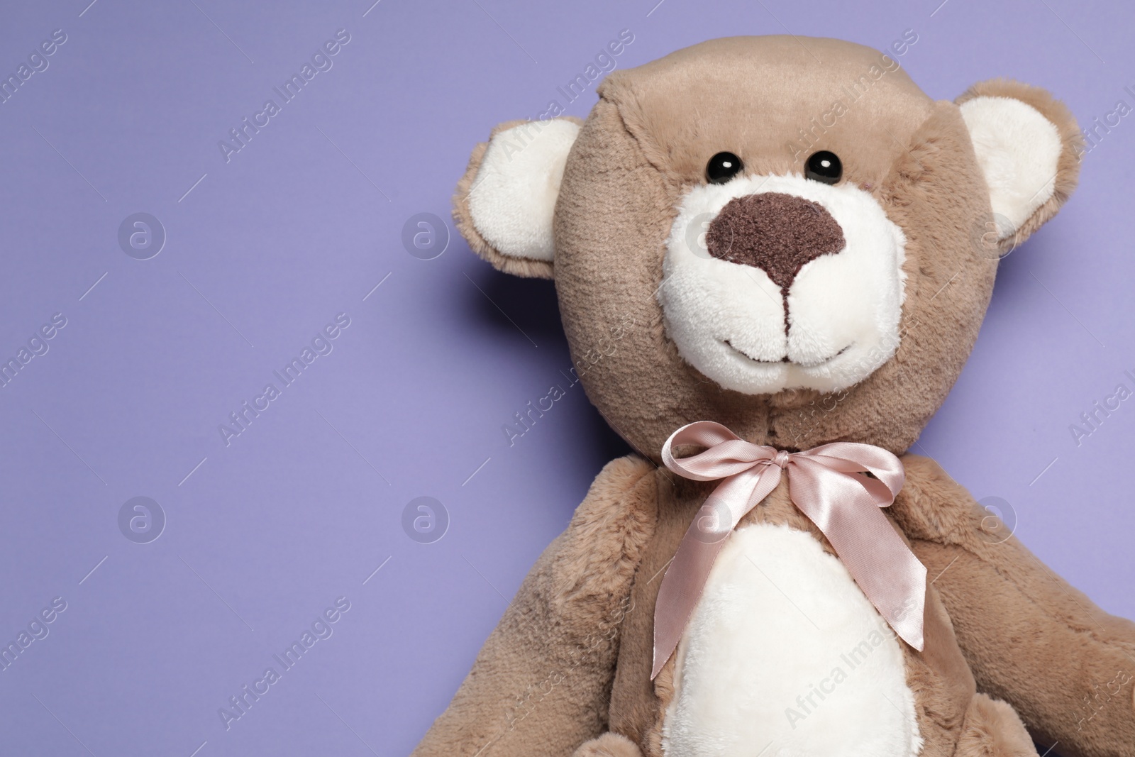 Photo of Cute teddy bear on light purple background, top view. Space for text