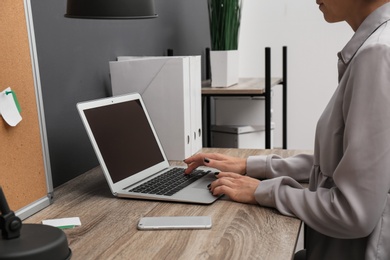 Photo of Woman using laptop at table, closeup. Stylish workplace